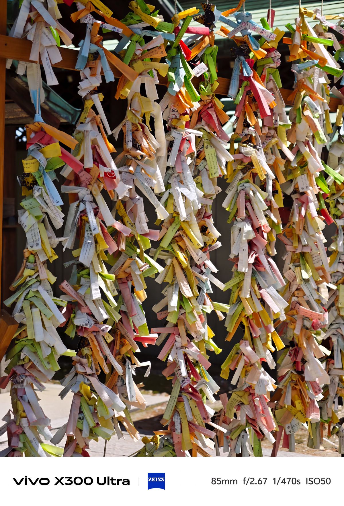 Dense rows of folded, colorful paper fortune strips tied tightly to wooden frames at a shrine.