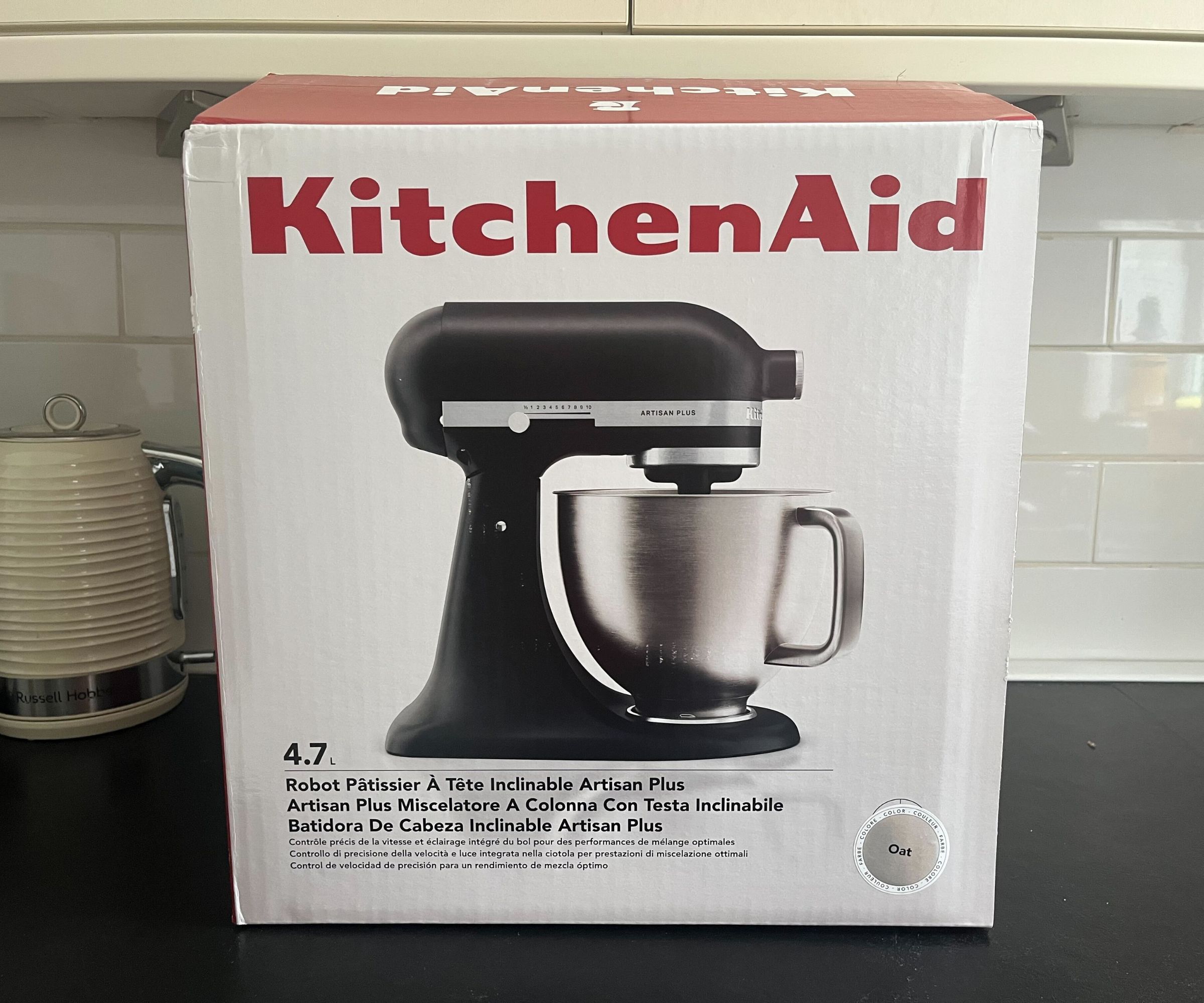 A KitchenAid artisan plus stand mixer box with a picture of a black stand mixer on the front.