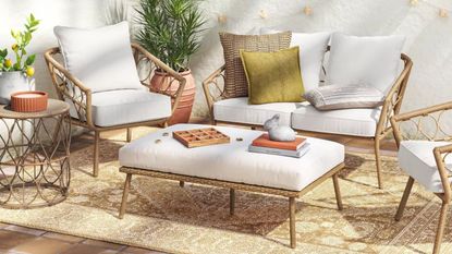 rattan wicker patio furniture with small love seat, two tub chairs, and an ottoman sat on a vintage-style beige rug