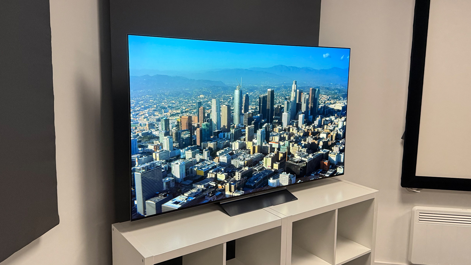 LG C6 OLED TV on white shelving unit with overhead city view on screen