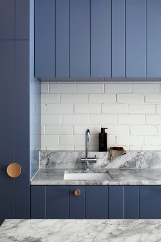 A retro inspired blue kitchen with tongue and groove cabinets and round wooden handles