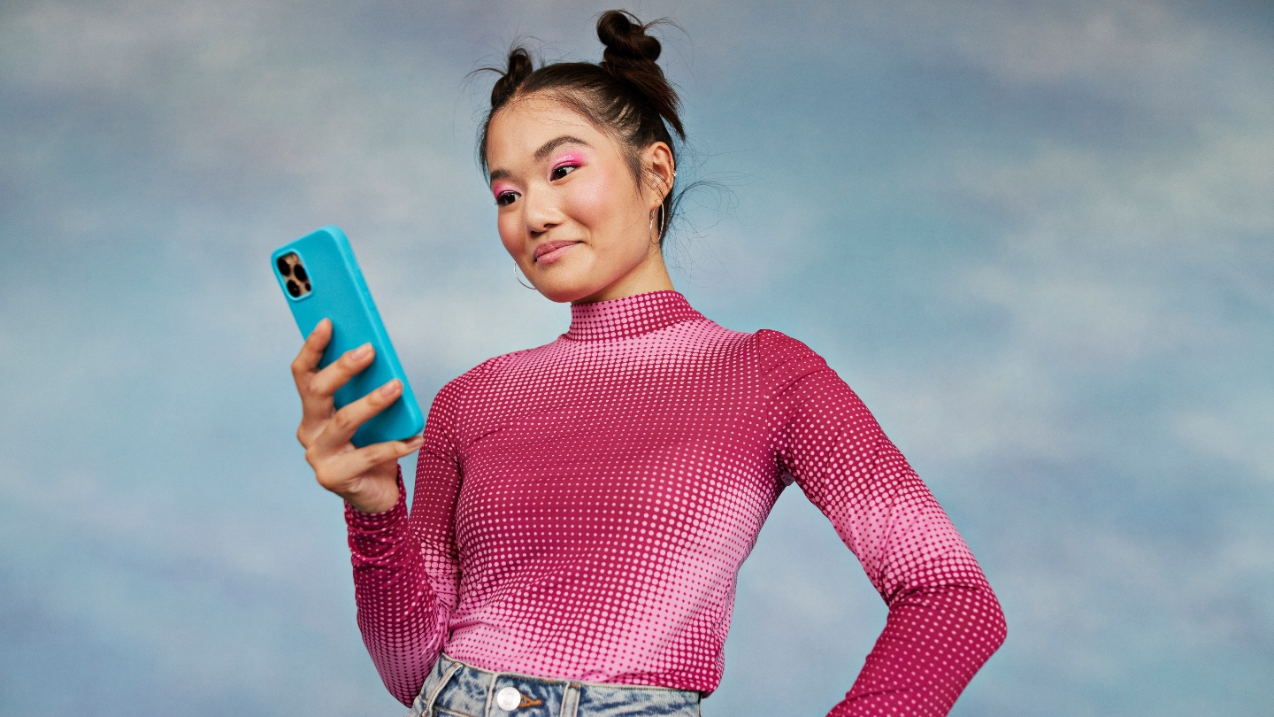 Girl wearing pink shirt looking down at her phone and smiling