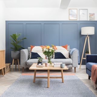 Grey sofa in front of blue painted panelled wall in snug room