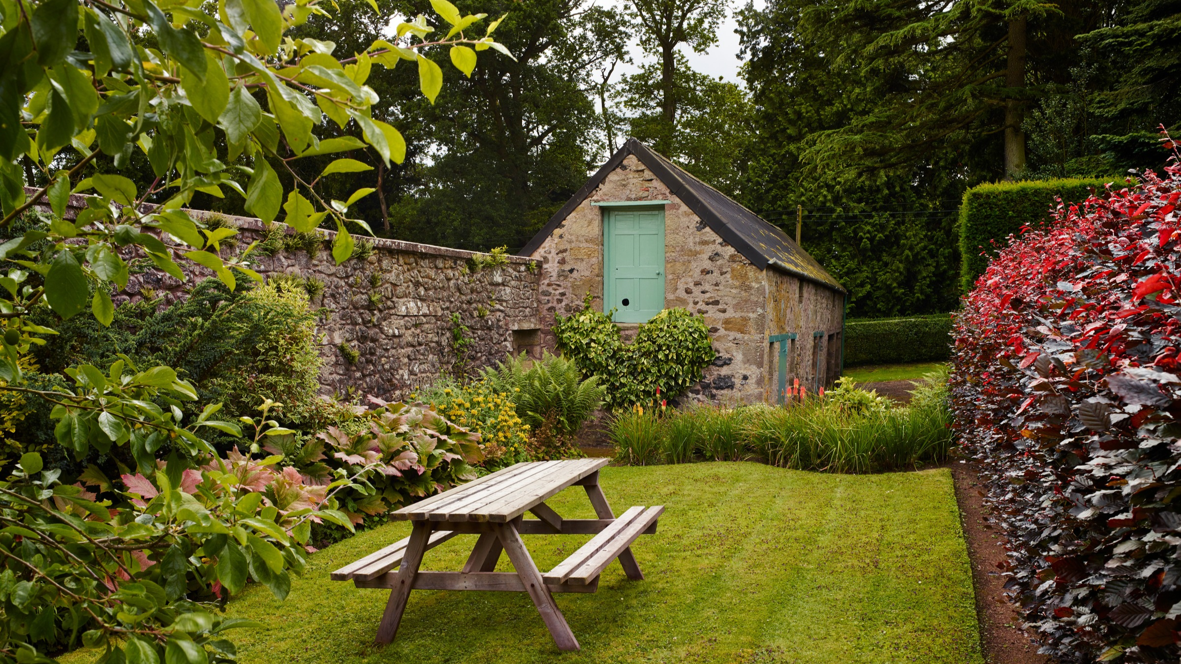 Flower and plant beds. Lawn, table and benches.