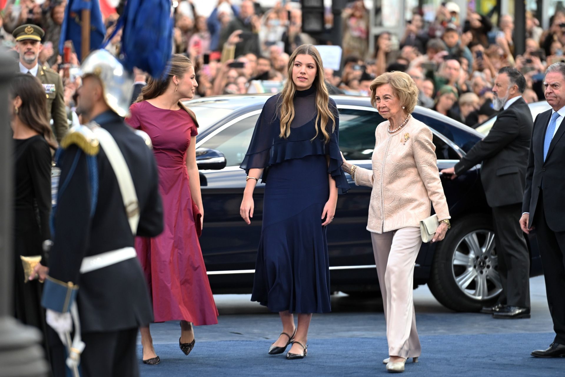 Queen Sofia putting her arm on Infanta Sofia's back as they exit a car