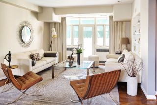 White lounge with accent low leather chairs adjacent to couches sat over quietly patterned gray area rug