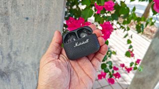 Marshall Motif II in charging case held in hand with flowers in the background