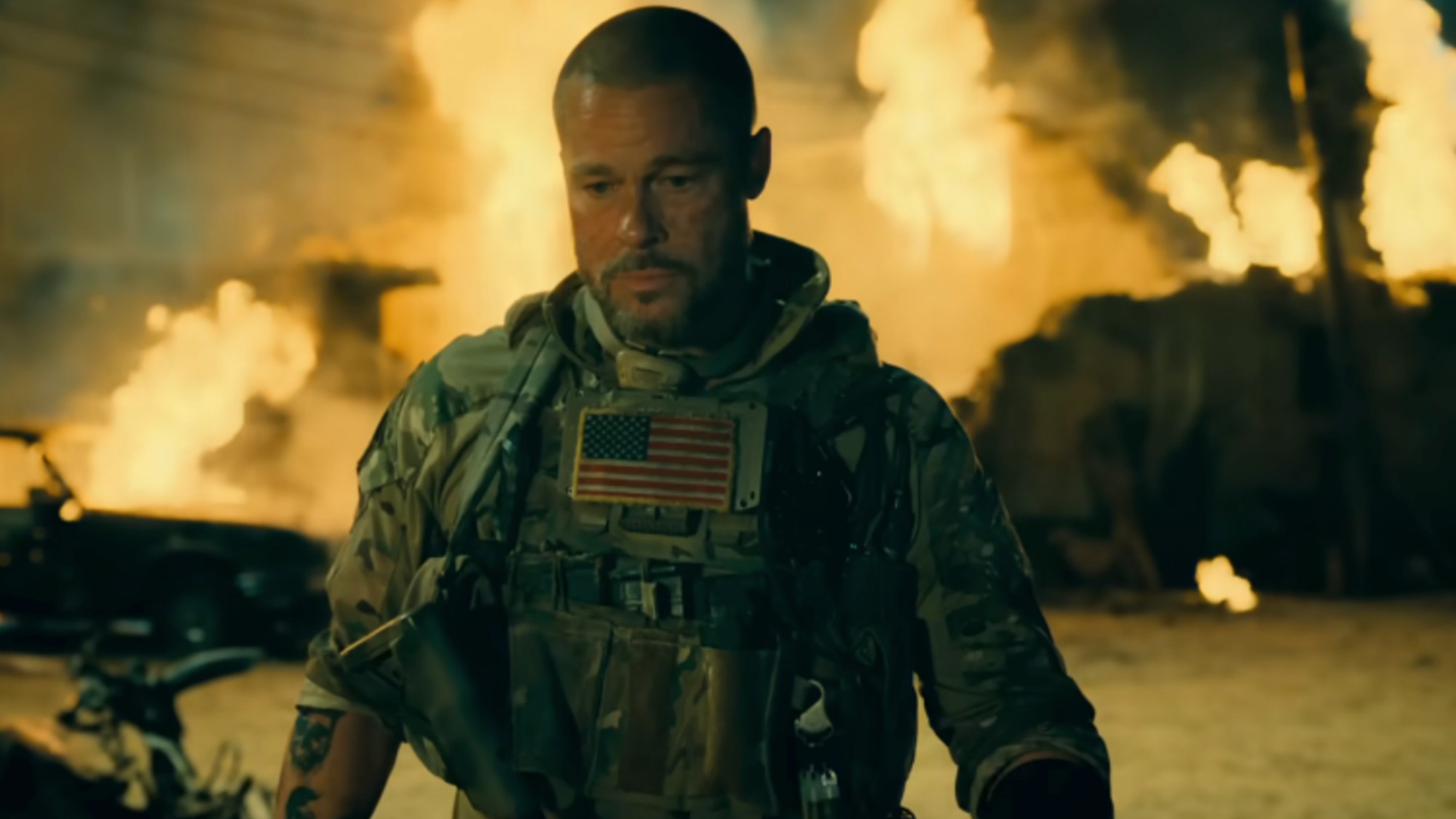 Brad Pitt looking solemn while wearing army fatigues, with fires behind him in Heart of the Beast