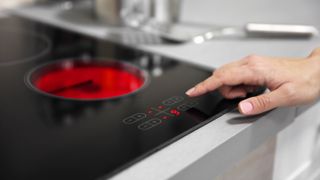 Someone turning up the heat setting on an electric cooktop