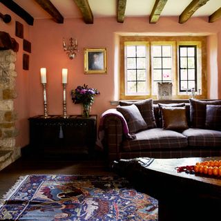 living room with oink wall wooden beams on ceiling and sofa with cushion