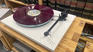 Rega Planar 3/Nd3 turntable package slight angle on wooden hi-fi rack with purple vinyl record