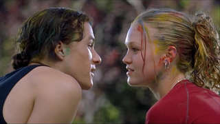 A scene from 10 Things I Hate About You, where Patrick and Kat gaze at each other closely, their faces speckled with colorful paint after a playful paintball fight.