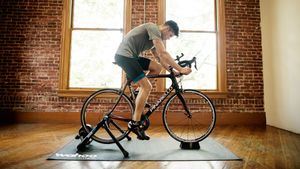 The best turbo trainer can help you get road fit, just like how the person on this picture, riding a turbo indoors in front of large windows