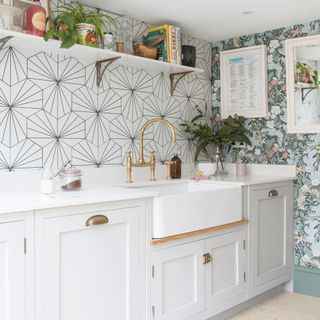 Kitchen with dual wallpaper, white cabinets and Belfast sink