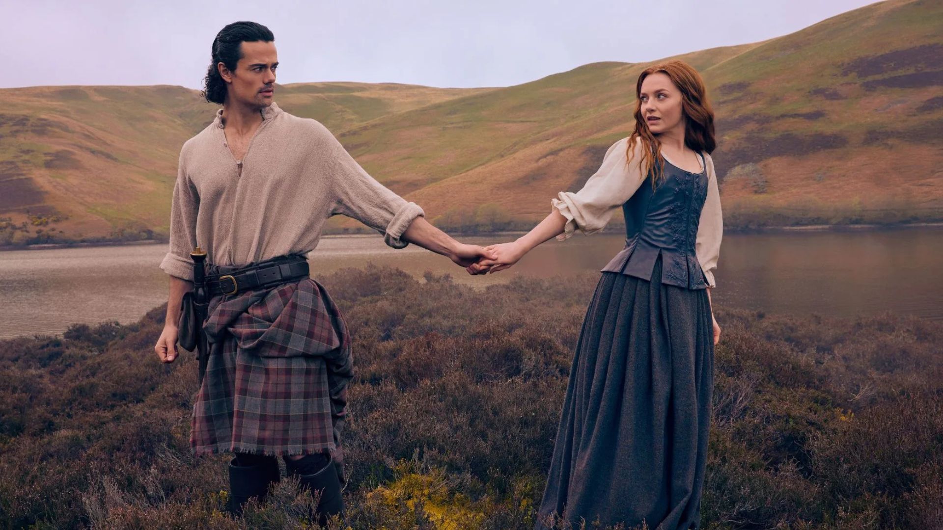Brian and Ellen hold hands in a field