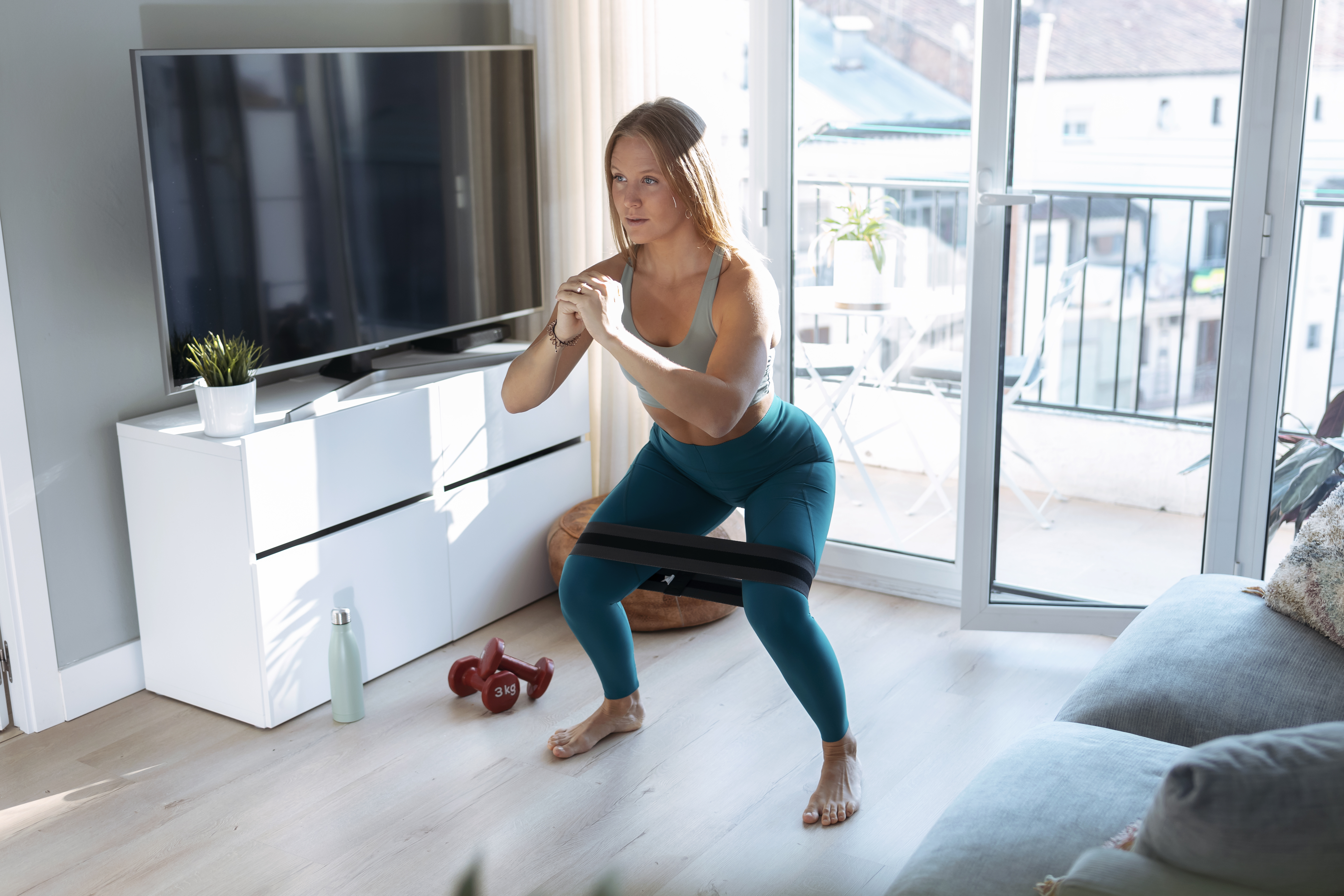 Woman doing squat at home with resistance band