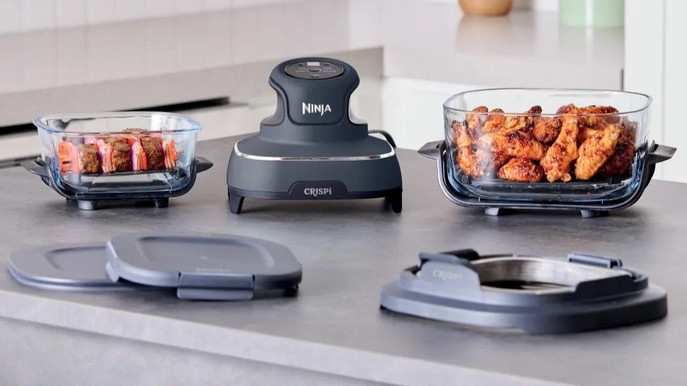 Ninja Crispi air fryer on kitchen counter with food in travel containers