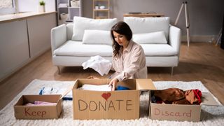 A woman sorting her belongings into three boxes