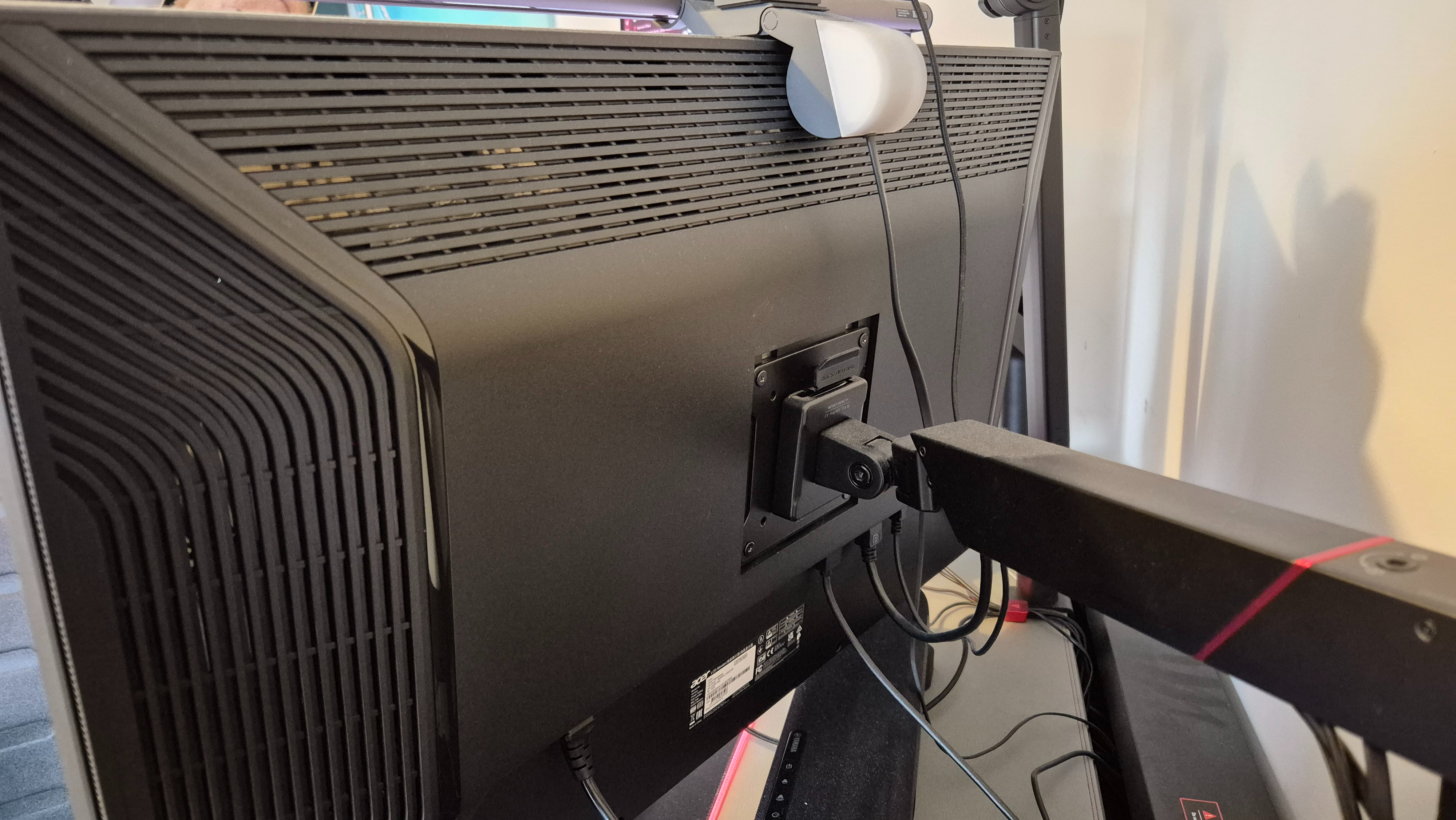 A picture of the Acer Predator X32QFS's rear while mounted on a monitor arm.