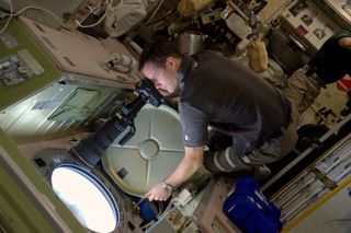 European Space Agency astronaut Thomas Pesquet takes photos through a window at the International Space Station.