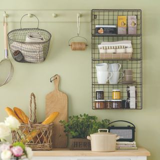 Green-painted kitchen with a wire shelf
