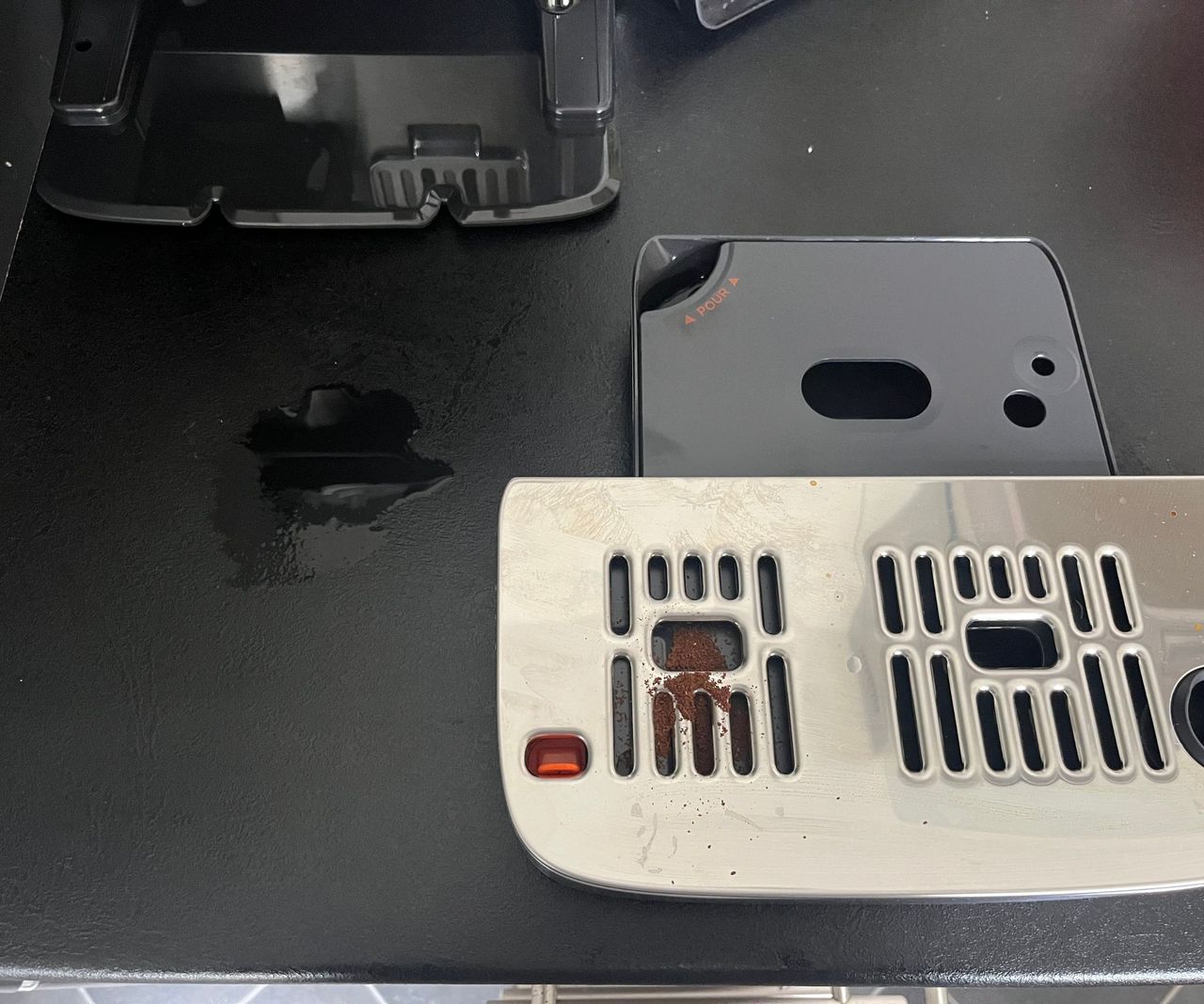 The drip tray removed from the Ninja Luxe Caf&eacute; Mini showing some spilled water beneath.