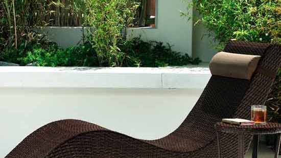 brown sun lounger on white floor and green plants