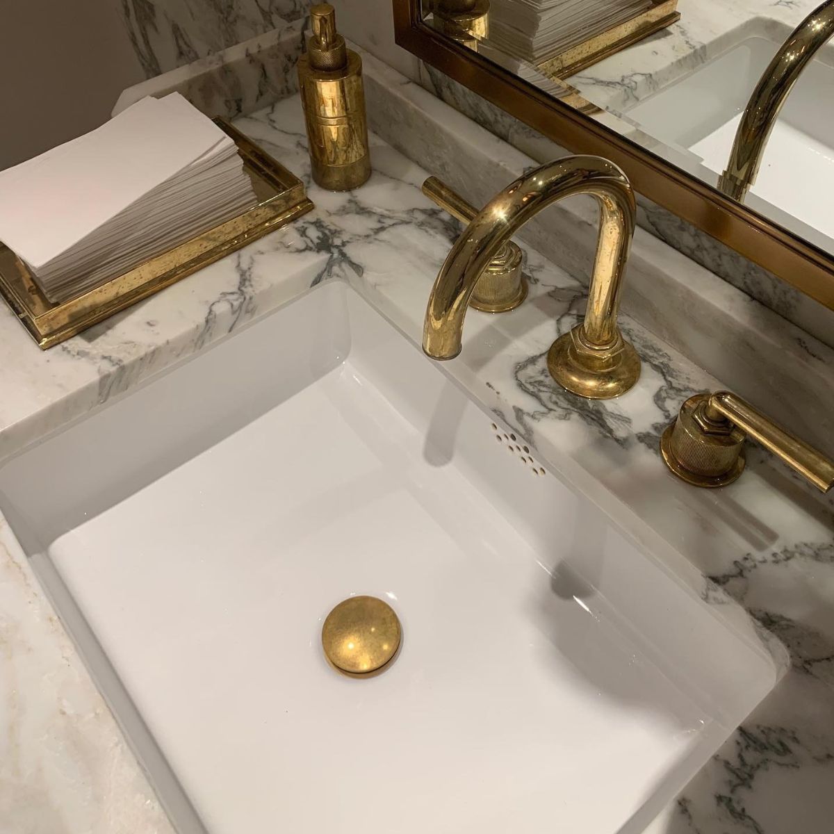 A white a grey marble sink with gold chrome taps and faucet