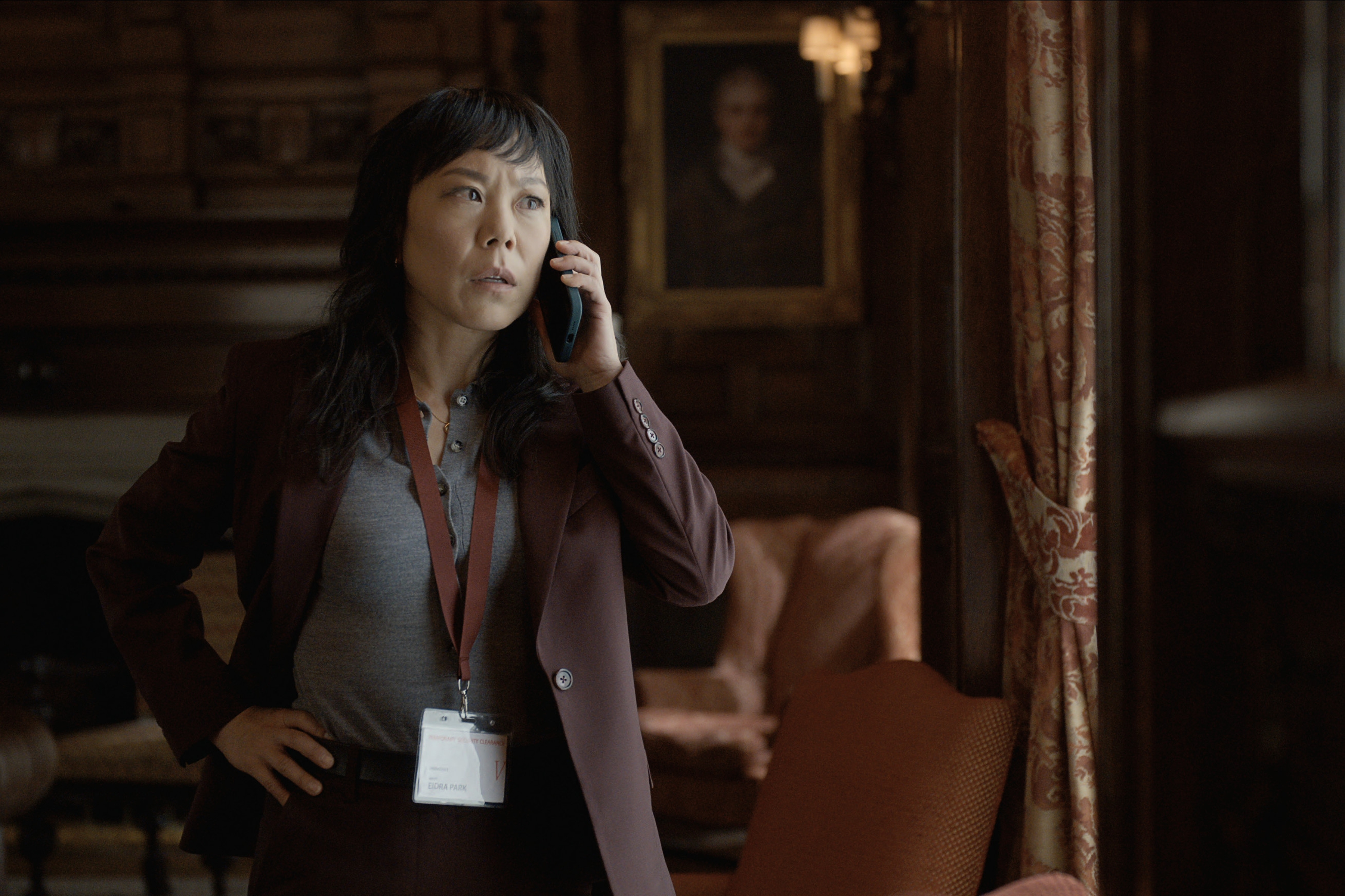 Ali Ahn on the phone wearing a blazer in an office in the diplomat season 3
