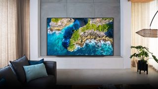 The LG CX OLED TV showing a piece of coastline, at back of stylish living room