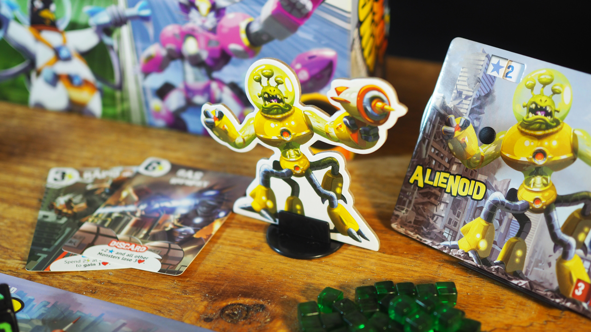 King of Tokyo Alienoid token and board, with cards, the game box, and green cubes visible on a table