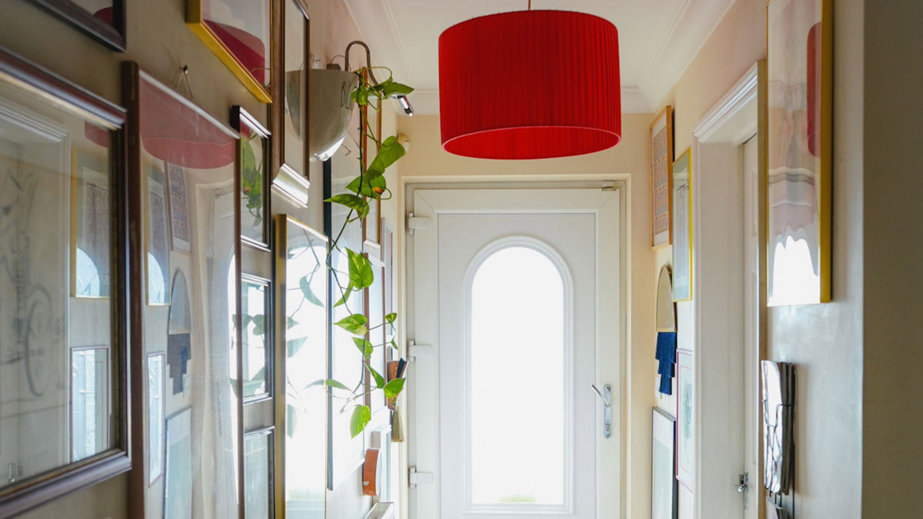 narrow hallway with art on the walls and bright red lightshade