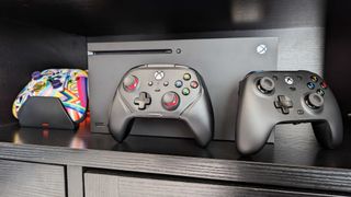 Image of the HyperX Clutch Gladiate in front of an Xbox Series X, alongside an Xbox Wireless Controller and GameSir G7.