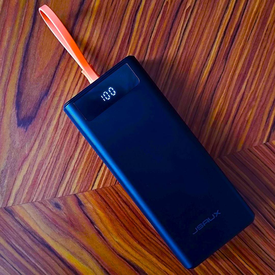 Jsaux 20000mah 65w power bank on woodgrain table.