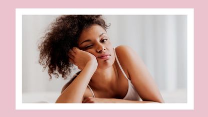 woman in bed with white tank top looking frustrated