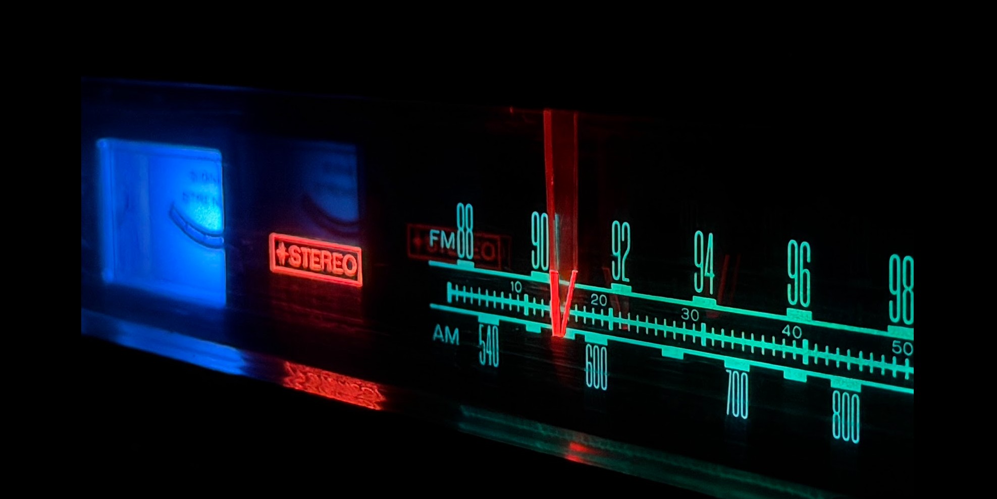 The blue, green and red lights of a refurbished stereo shining in a dark room.