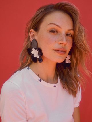 Kayla Wallace wears oversize floral earrings and a Chanel white t-shirt.