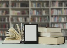 Photo of books and kindle in front of bookcase