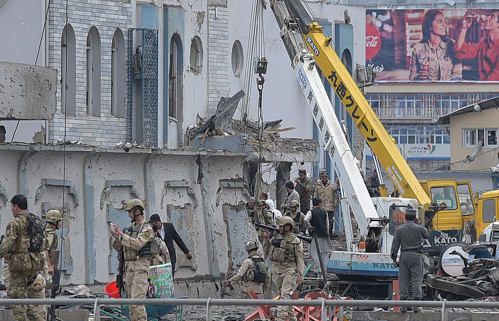 Afghan security officials inspect the damage from a suicide bomb in Kabul