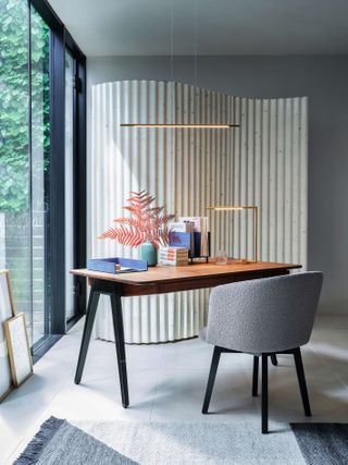 home office with retro desk and grey boucle chair, modern lighting, fall stem in vase, desk accessories