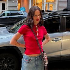 a woman wearing a red polo shirt and blue jeans