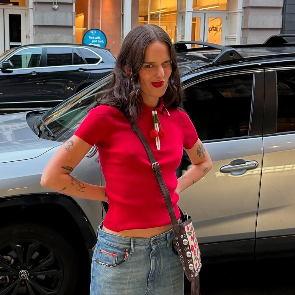 a woman wearing a red polo shirt and blue jeans