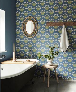 Blue/green bathroom with wallpaper, peg rail, mirror, painted bath tub, wood stool