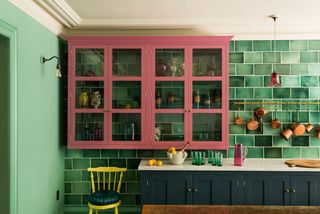 Kitchen with green tile wall, blue floor cabinets and pink wall cabinets