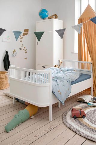 A modern white bed in a childrens room decorated with bunting