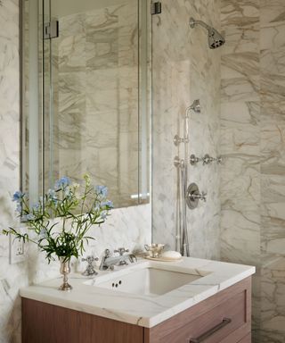 bathroom with mirrored medicine cabinet, wooden washstand with storage and marble worktop and marble walls