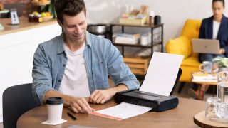 Canon TR160 compact printer being used by man in a cafe