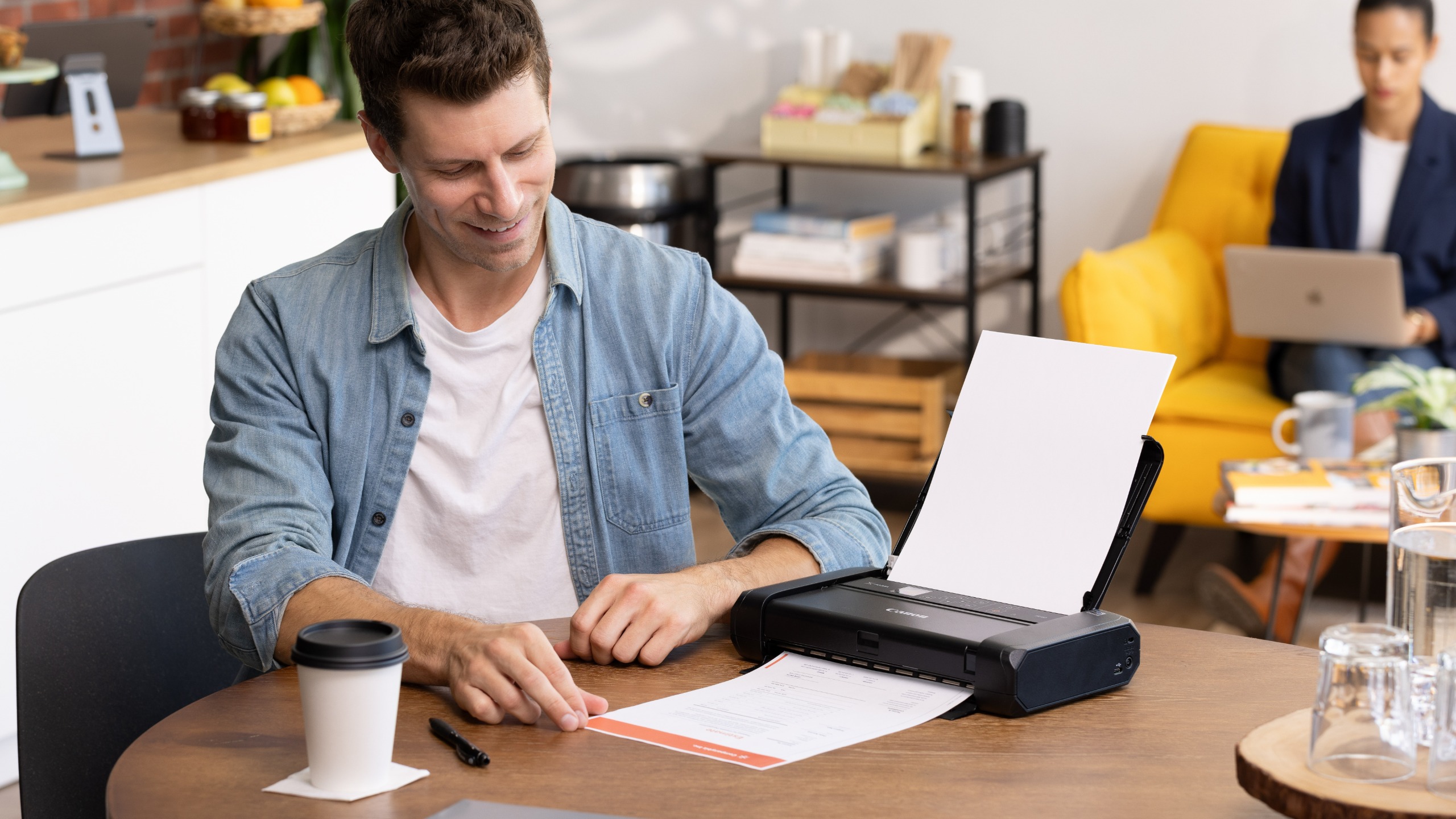 Canon TR160 compact printer being used by man in a cafe