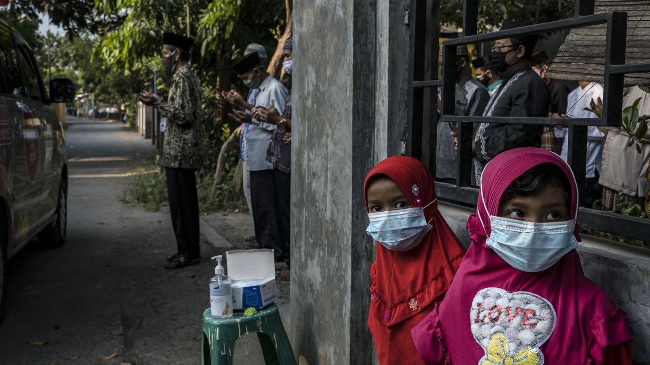 Two children stand as their relatives pray by an ambulance in Yogyakarta, Indonesia