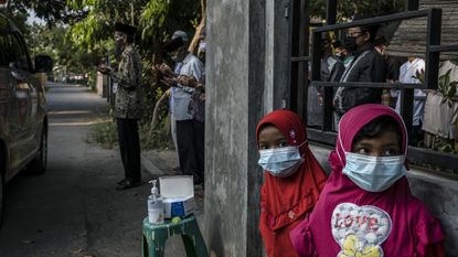 Two children stand as their relatives pray by an ambulance in Yogyakarta, Indonesia